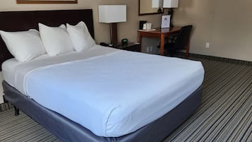 Una habitación de hotel con una cama grande, un escritorio, una silla, una lámpara y un reloj.