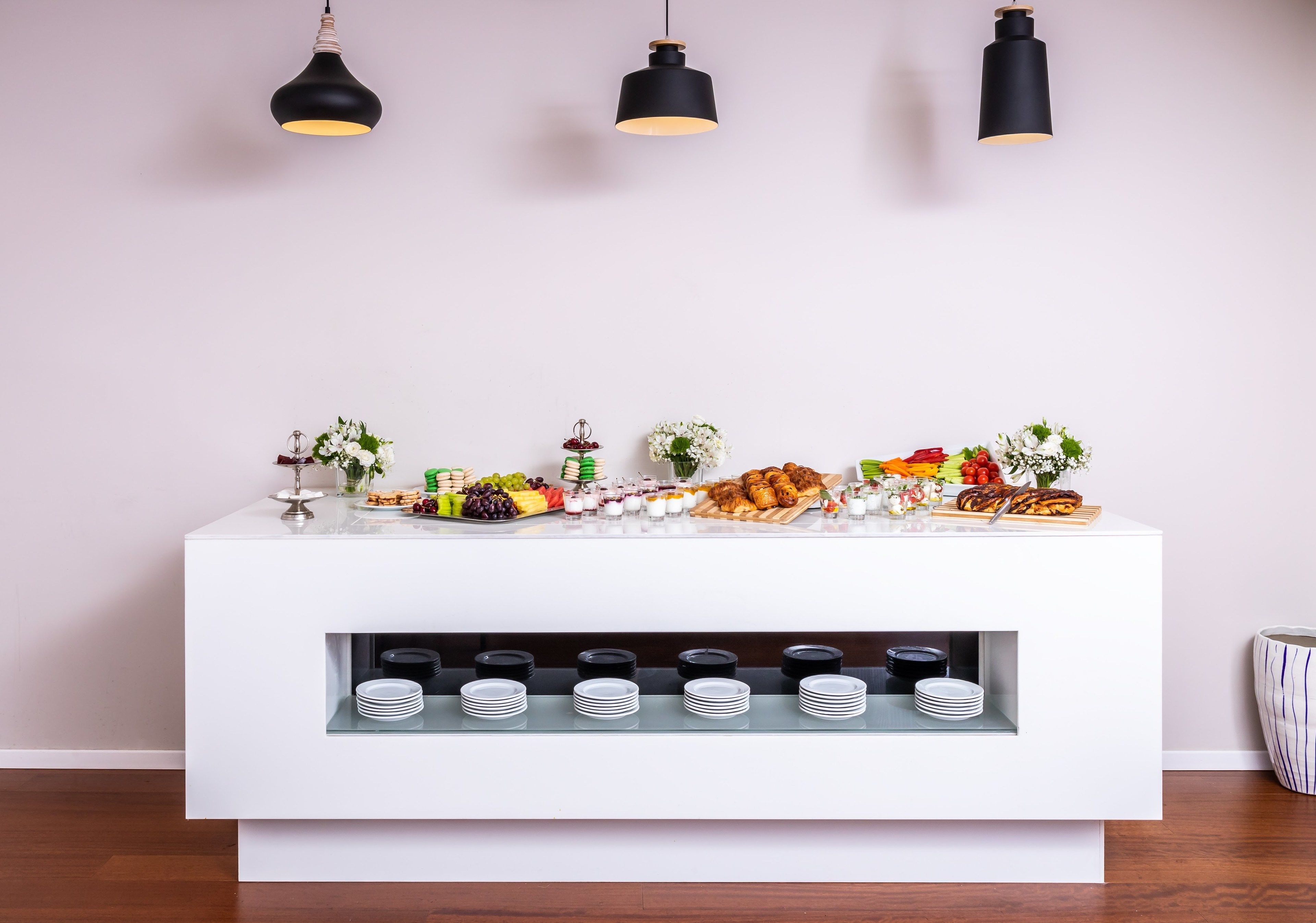 Taula de buffet blanca amb diferents aliments i una prestatgeria de vi.