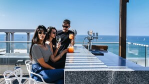 Een bar met uitzicht op zee, zitplaatsen en een toonbank met een drankje.