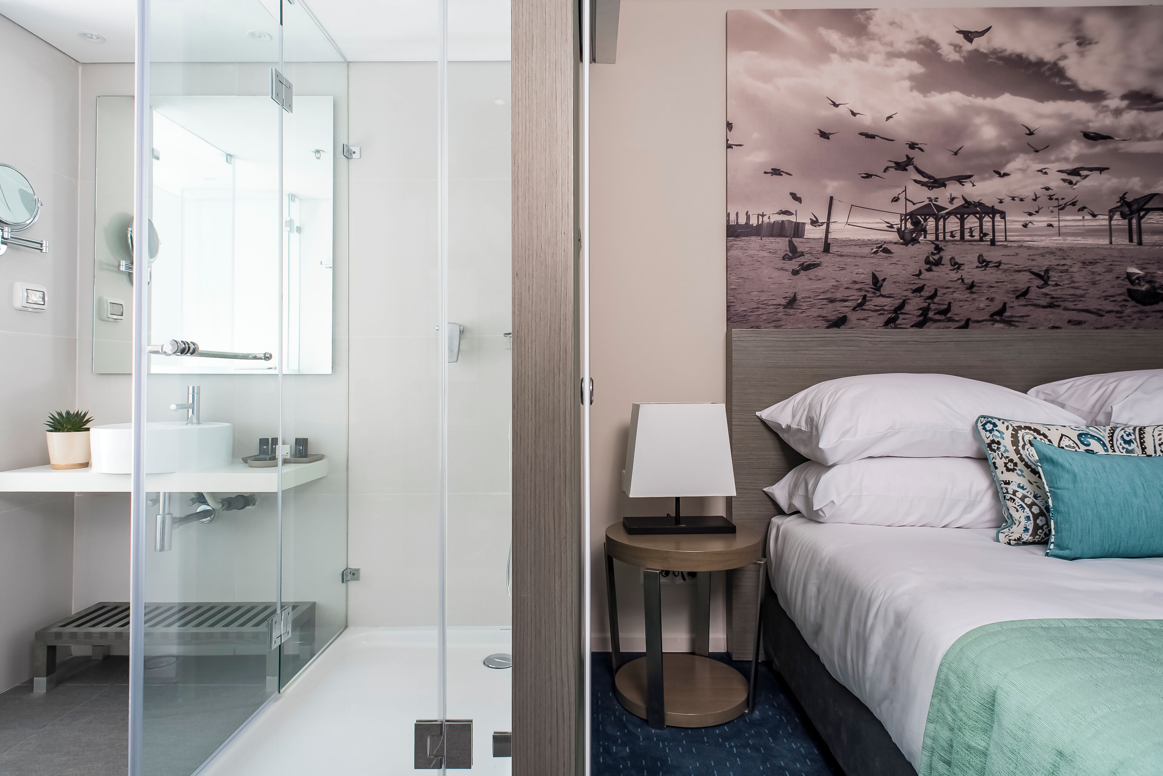 A modern bathroom with a glass shower enclosure, a sink, and a mirror.