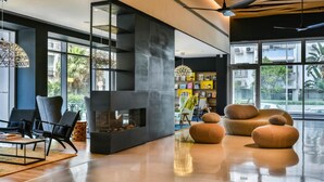 Een modern interieur met een open haard, zwart en oranje zitplaatsen en grote ramen.