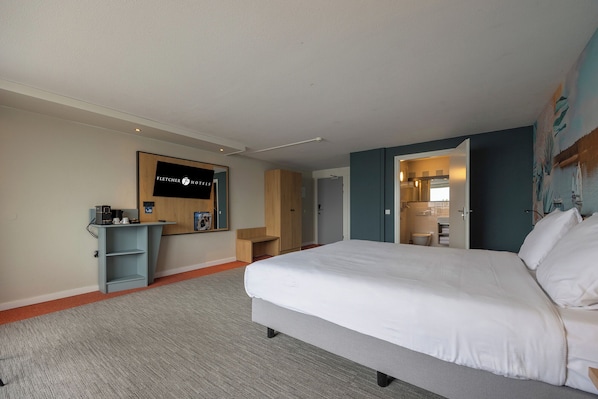 A hotel room with a bed, a desk, a mirror, and a bathroom visible through an open door. - Fletcher Hotel-Restaurant Loosdrecht - Amsterdam (Loosdrecht)