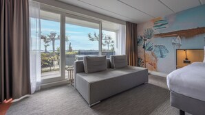A hotel room with a sofa, a bed, a view of the outdoors, and a mural on the wall. - Fletcher Hotel-Restaurant Loosdrecht - Amsterdam (Loosdrecht)