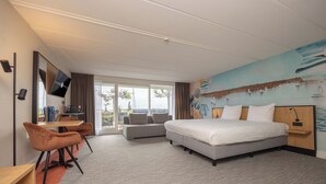 A hotel room with a bed, a desk, a chair, a sofa, a TV, and a view of the outdoors. - Fletcher Hotel-Restaurant Loosdrecht - Amsterdam (Loosdrecht)