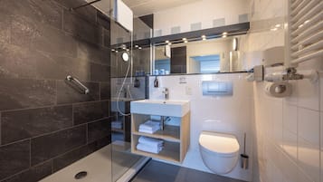 Uma casa de banho moderna com chuveiro em cabine de vidro, lavatório branco e sanita.