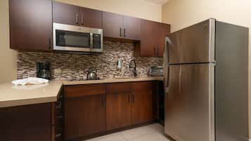 Una cocina moderna con armarios de madera oscura, electrodomésticos de acero inoxidable, incluyendo un microondas y un refrigerador, y un rebozado de azulejos.