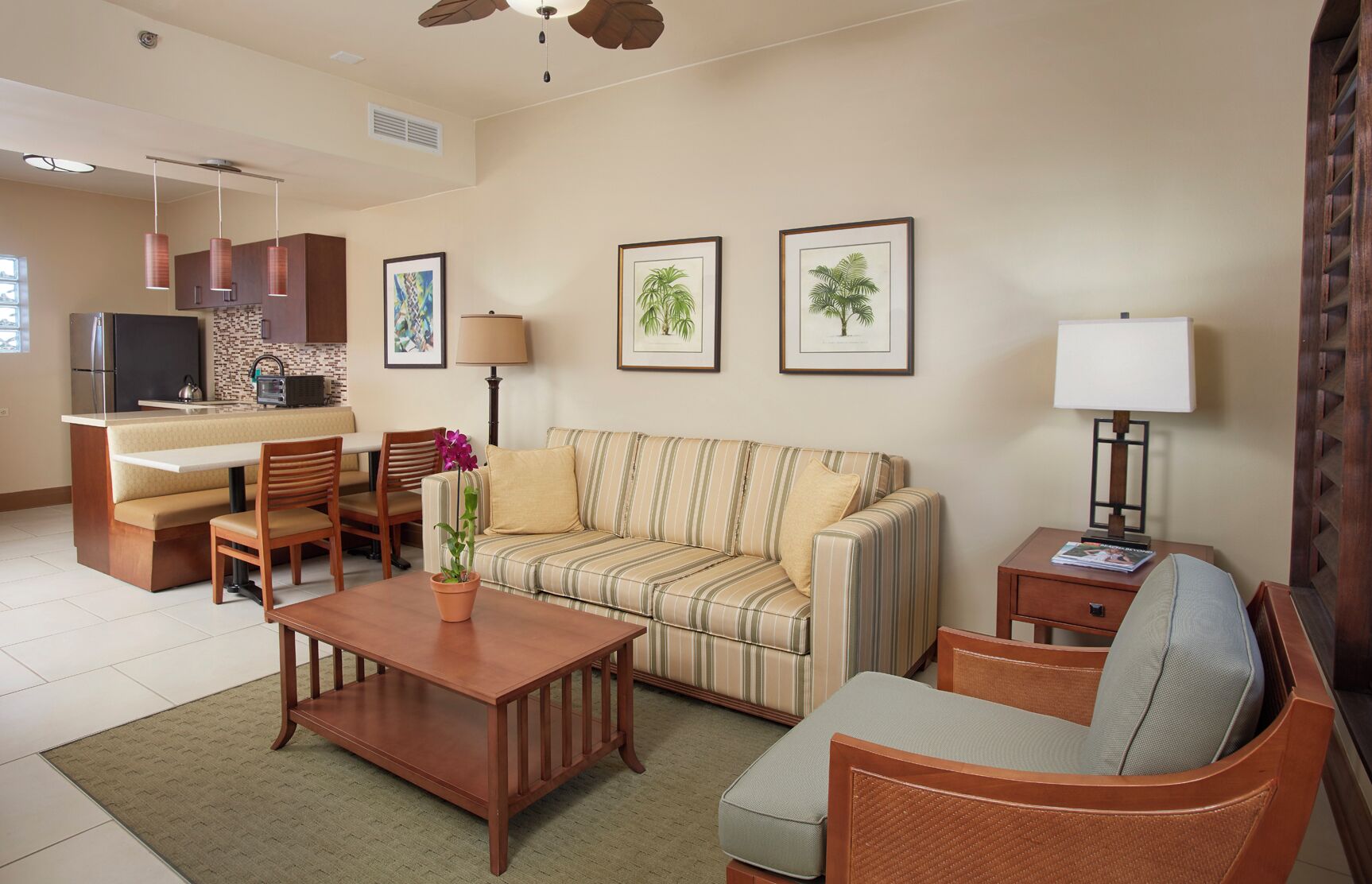 A living room with a sofa, a coffee table, a TV, and a kitchen area with a refrigerator and microwave.
