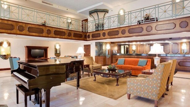 Un hall d’entrée spacieux, agrémenté d’un magnifique piano à queue, de sièges confortables, d’un plafond haut et d’un balcon.