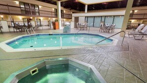 Une piscine intérieure avec des chaises longues et des tables, un jacuzzi et un espace de détente abrité.