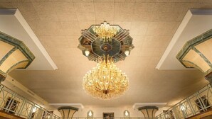 Un vaste hall orné d’un grand lustre et doté d’un balcon avec une balustrade.