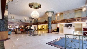 Un hall d’entrée spacieux, agrémenté d’un magnifique lustre, d’un piano et d’un comptoir d’enregistrement.
