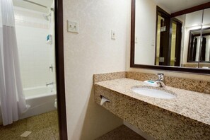 A bathroom with a sink, mirror, and shower.