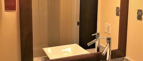 A bathroom with a large mirror, two sinks, and a vanity with toiletries.