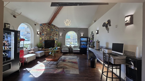 A spacious living area with a stone fireplace, comfortable seating, a bar area, and large windows. - Ramada by Wyndham Anchorage (Anchorage)