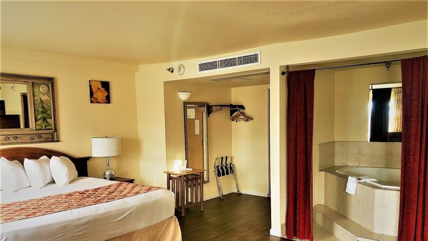 Hotelkamer met een bed, bureau, stoel, douche en een badkamer met bad.