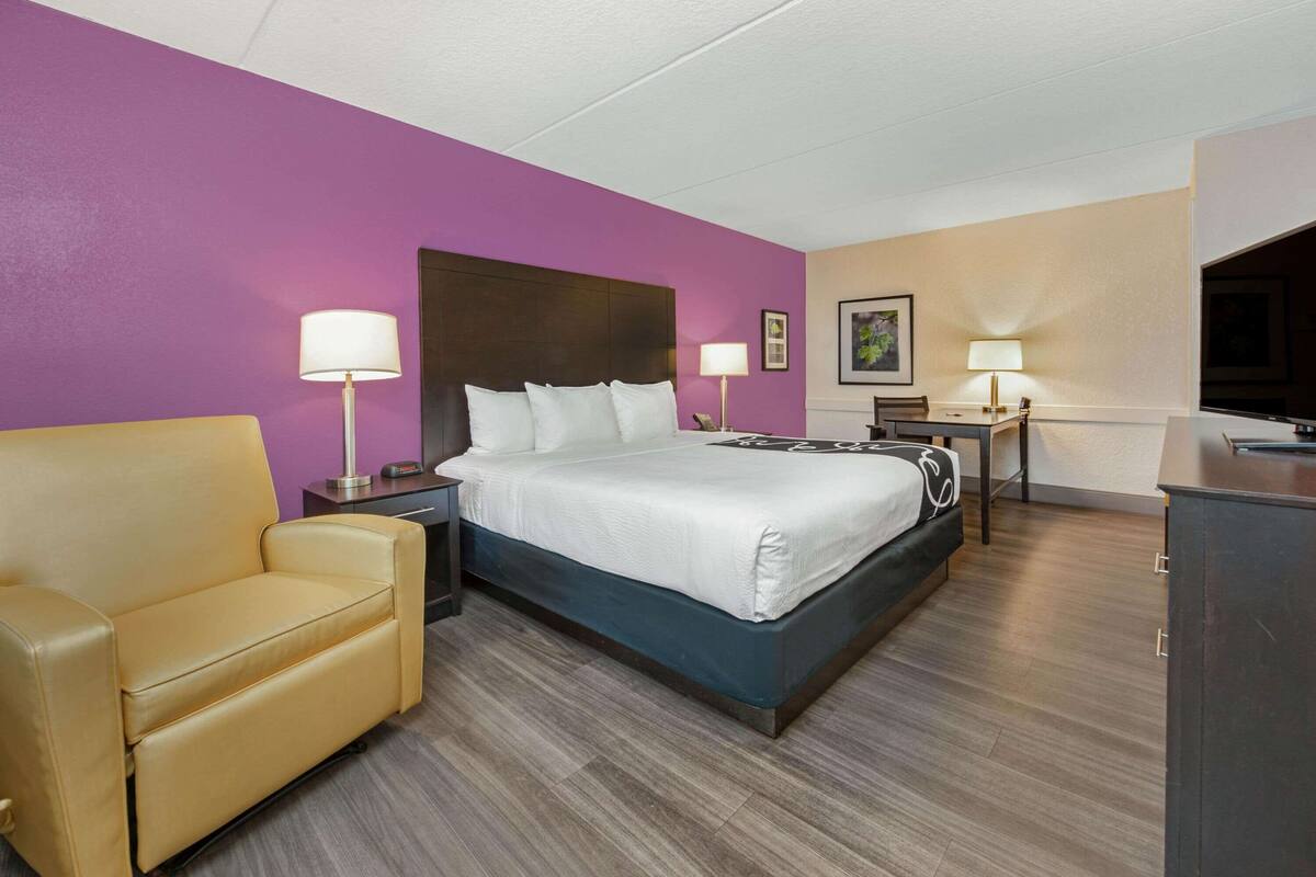 Une chambre d’hôtel comprenant un lit, un canapé, deux tables de chevet avec des lampes, un bureau avec une chaise et un téléviseur.