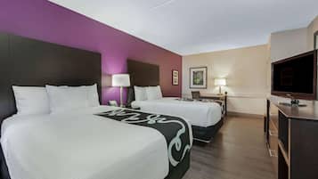 Una habitación de hotel con dos camas, televisión, escritorio y una silla.