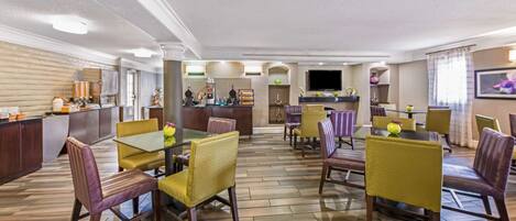 A spacious dining area with multiple tables and chairs, a bar area, and a television screen.