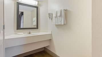Een badkamer met een wit wastafel, een spiegel en twee handdoeken die aan een handdoekhouder hangen.