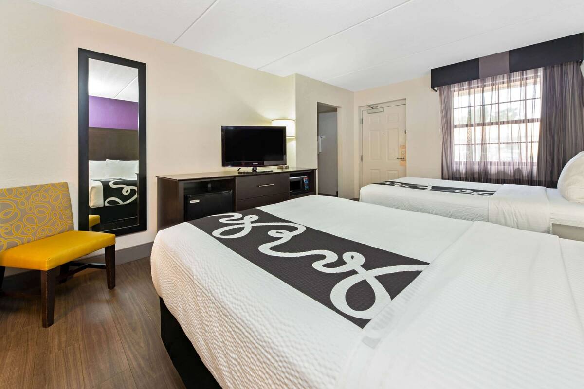 Une chambre d’hôtel avec deux lits, une télévision, un bureau et une chaise.