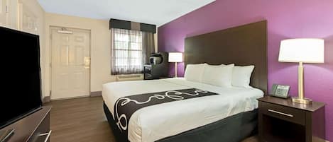 A hotel room with a bed, bedside lamps, a TV, and a desk with a lamp.