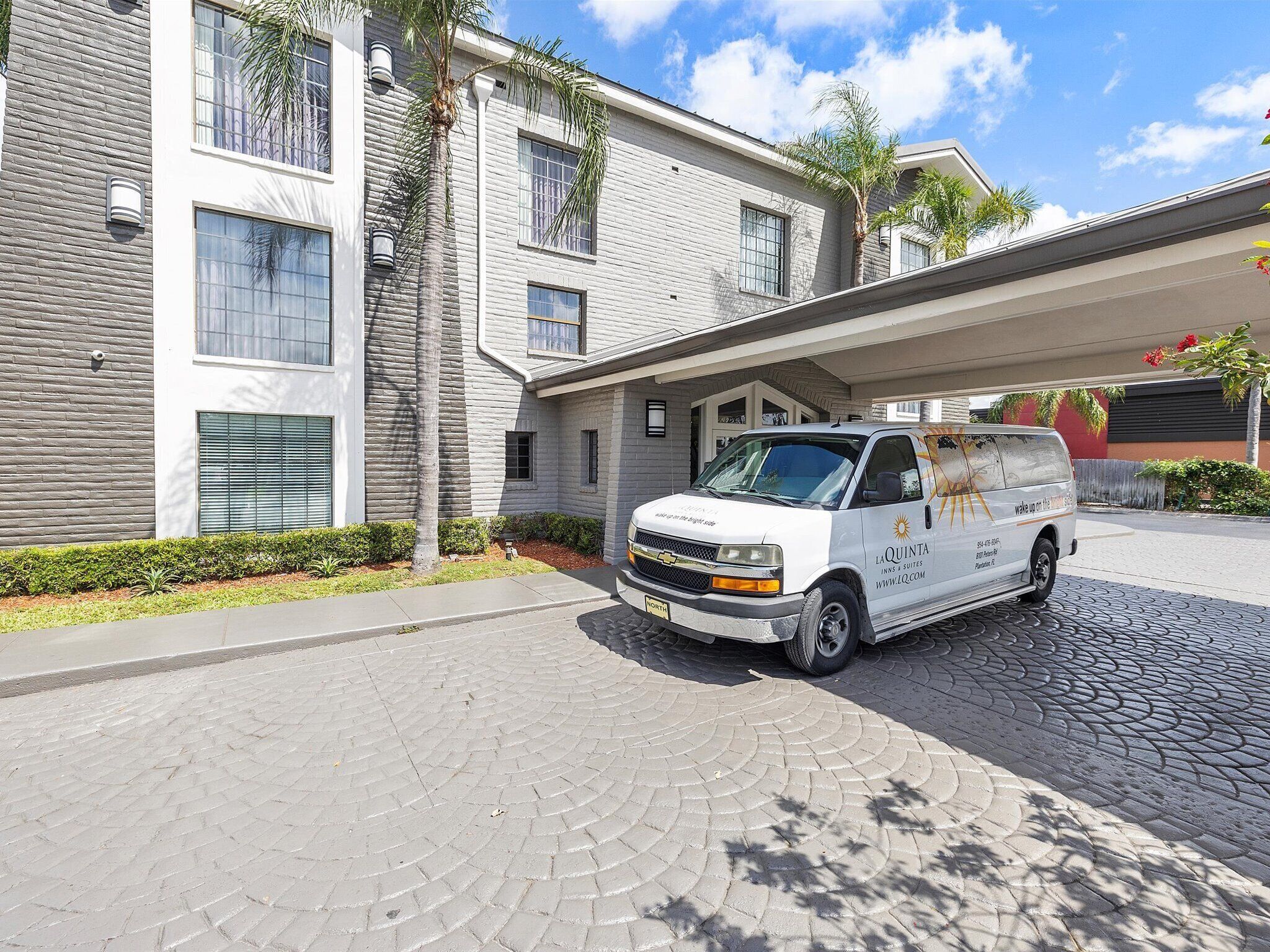 A white van parked in front of a modern building with a stone facade and large windows.