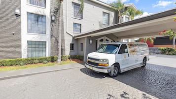 A white van parked in front of a modern building with a stone facade and large windows.