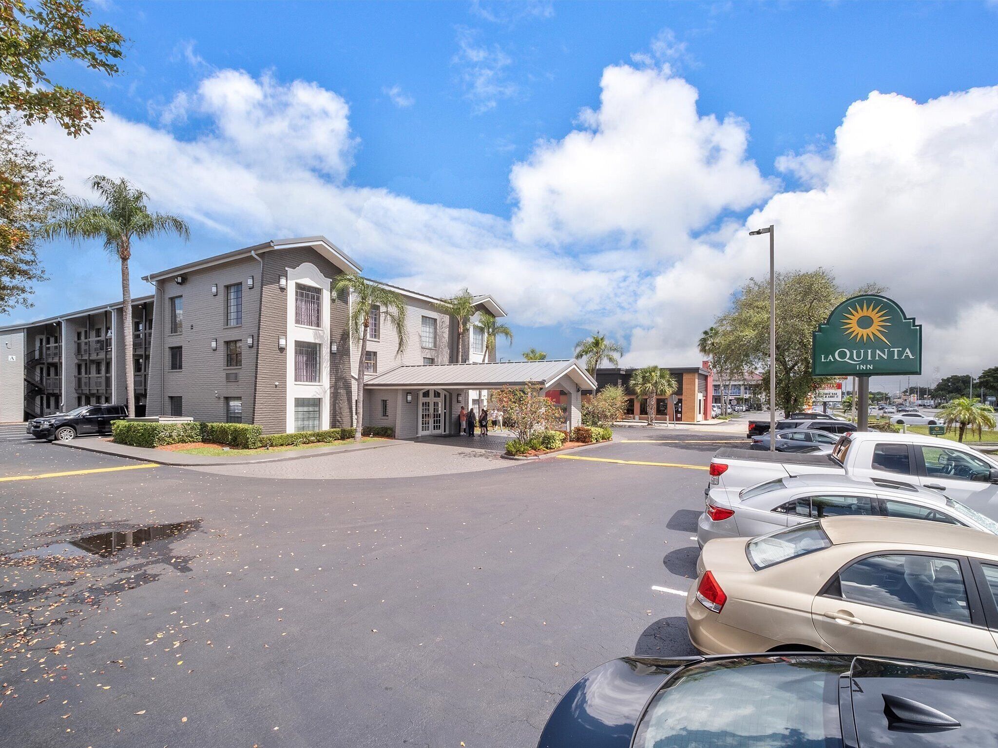 A hotel with a modern design, a parking lot, and a clear sky.