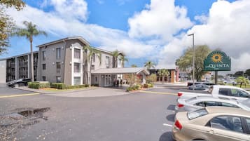 Een hotel met een modern design, een parkeerplaats en een heldere lucht.