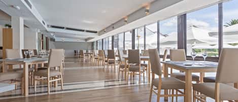 A spacious restaurant with high ceilings and large windows offering views of the outdoors.