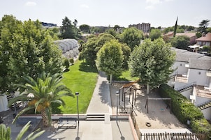 A residential area with a well-maintained lawn, a swing set, and a staircase leading to a building with multiple balconies.
