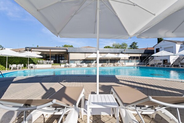 Una piscina al aire libre de temporada, sombrillas
