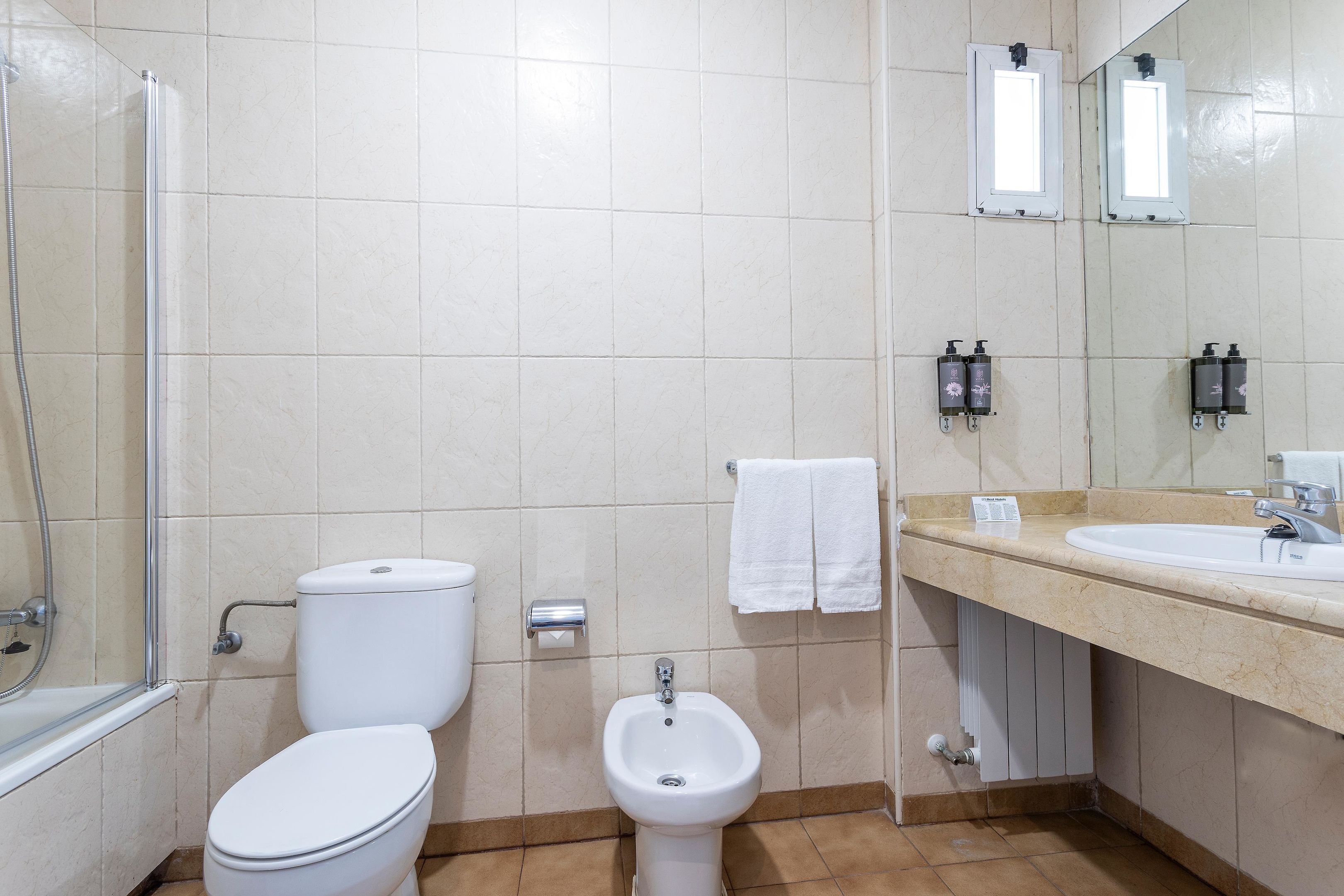 A bathroom with a toilet, bidet, and a sink.