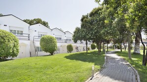 Un sendero conduce a un edificio blanco con escaleras y un césped cuidado.