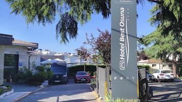 L’entrée d’un hôtel, avec une enseigne indiquant « Hotel Best Osuna », une zone de stationnement et un bâtiment doté d’un toit en tuiles.