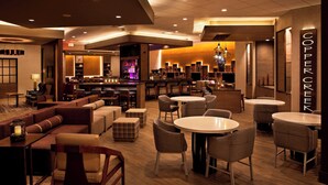 Un hall d’hôtel moderne doté d’un bar, de différents espaces de détente et d’une enseigne bien visible indiquant « COPPER CREEK ».