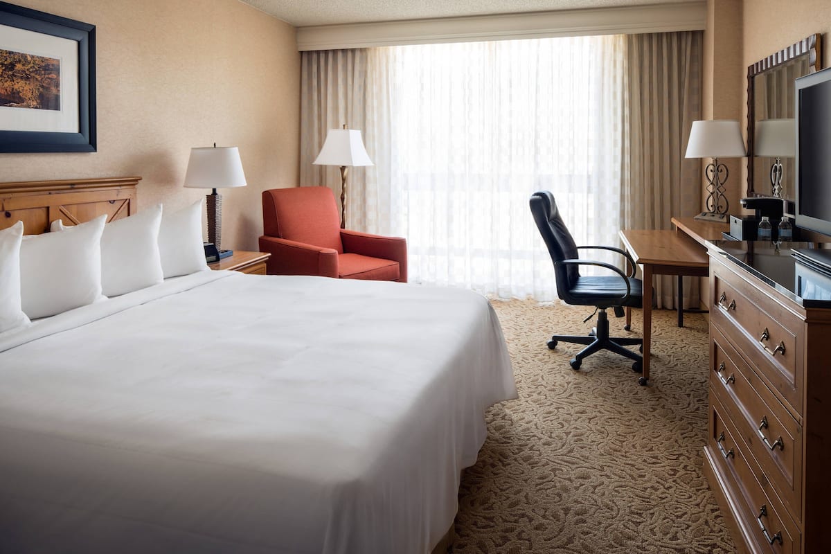 A hotel room with a large bed, a desk with a computer, a chair, and a TV.