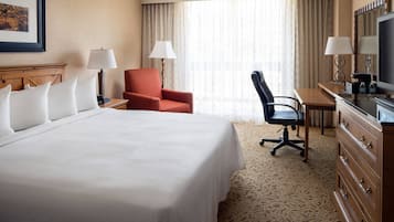 A hotel room with a large bed, a desk with a computer, a chair, and a TV.