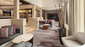 Un moderno vestíbulo de hotel con sofá, sillones, una mesa de centro y una chimenea.