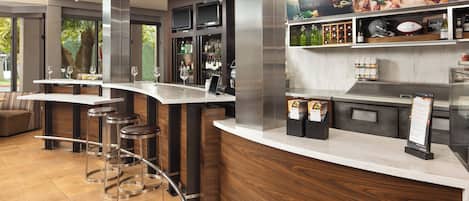 A modern bar area with high stools, a counter, and a wine display.