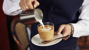 A person pouring milk into a cup of coffee.