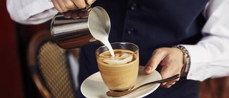 En person hælder mælk i en kop kaffe.
