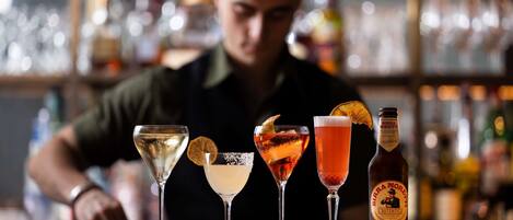 A bar counter with four different drinks and a bottle of beer.