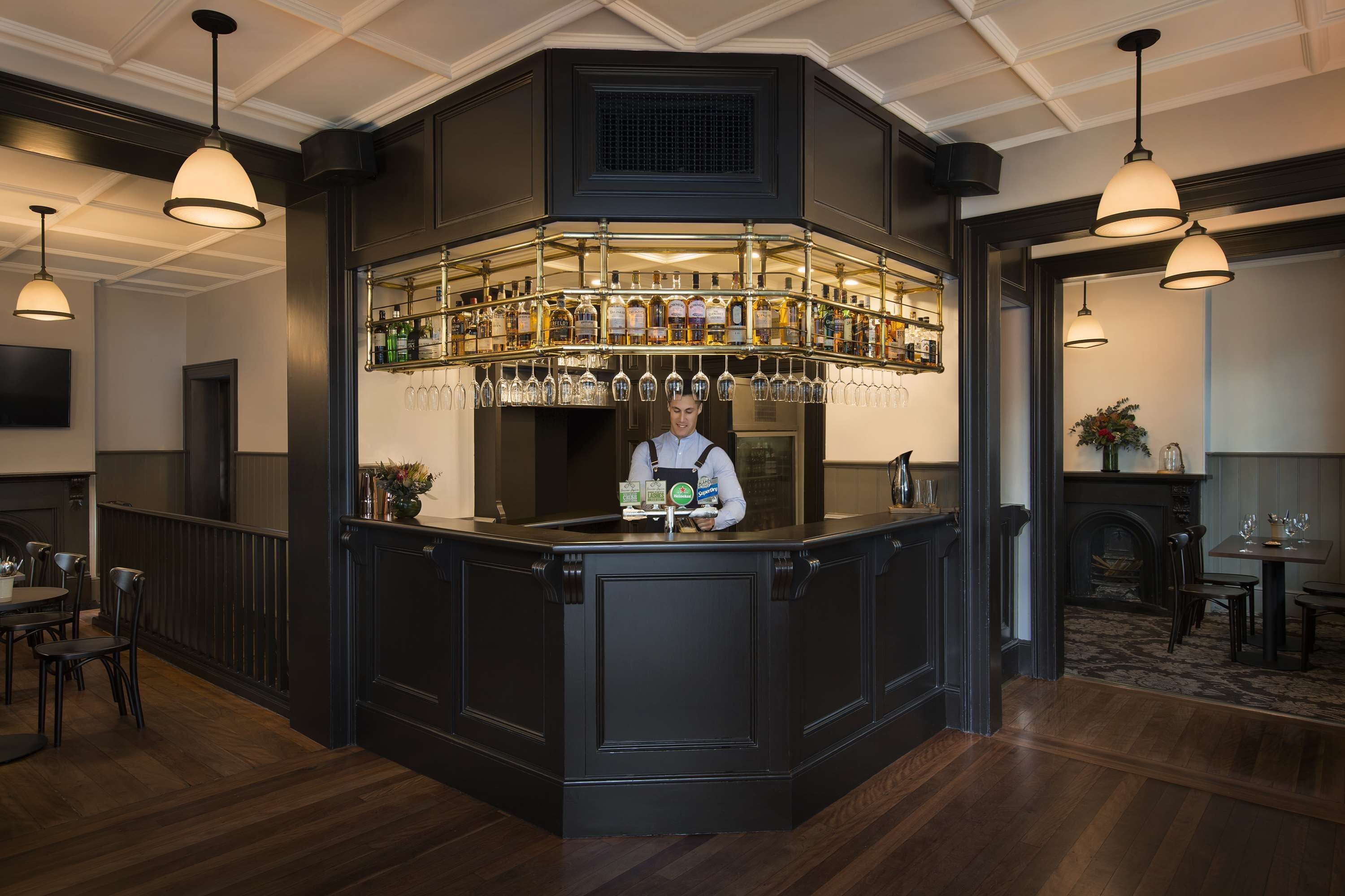 A bar area with a bartender, a wine rack, and a seating area with tables and chairs.