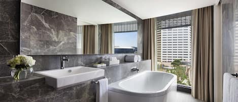 A modern bathroom with a large bathtub, a double sink, and a large mirror.