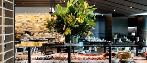 A buffet with various food items and a centerpiece of flowers.