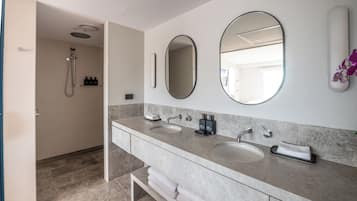 Un baño moderno con dos lavamanos, ducha y un espejo grande.
