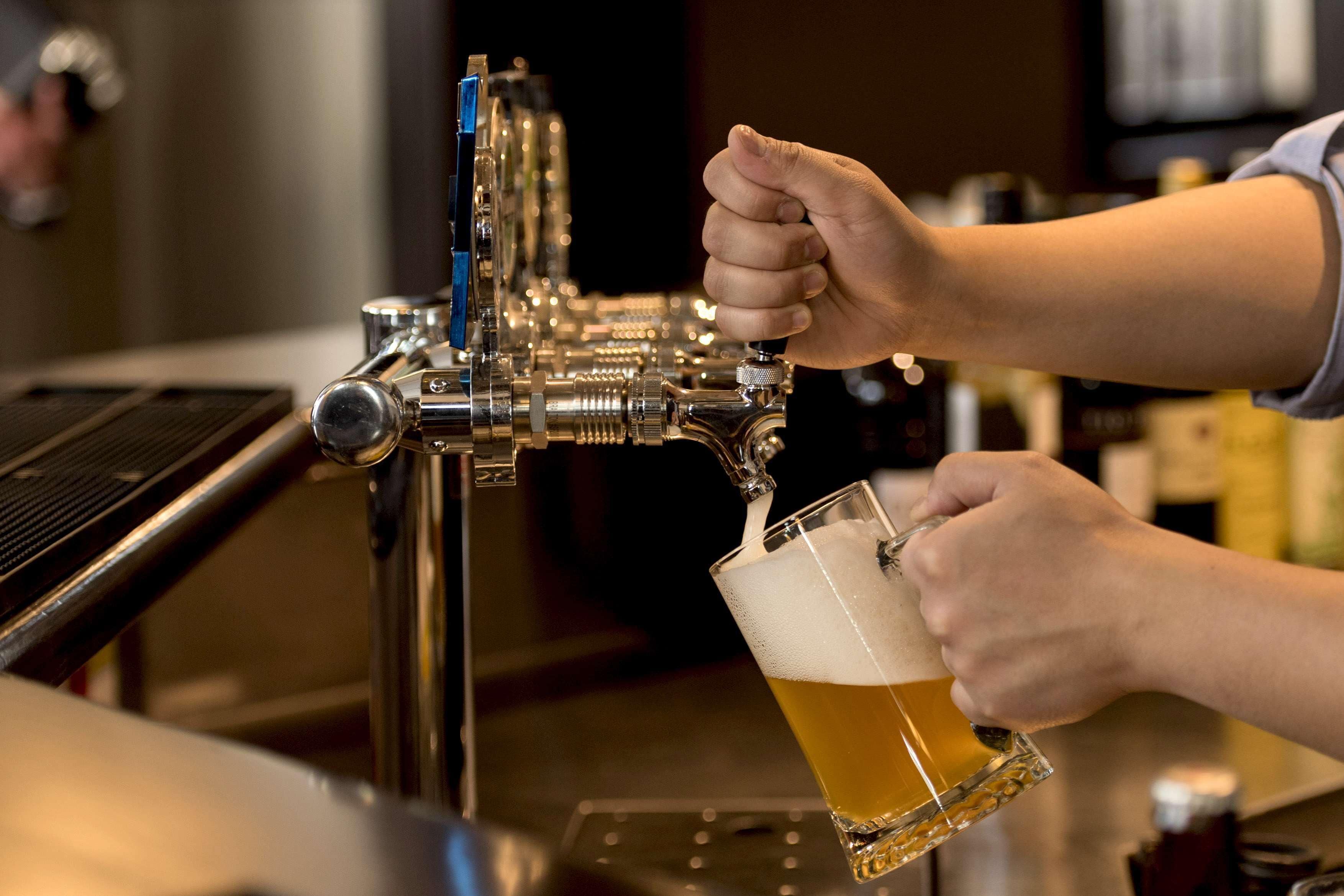 A person pouring beer from a tap into a glass.