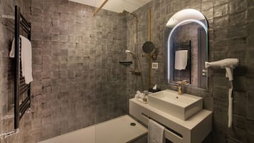 Uma casa de banho moderna com um espelho grande, lavatório embutido e chuveiro manual.