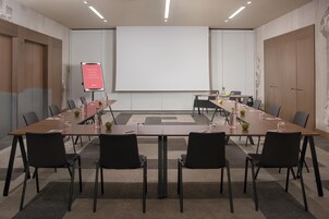 A conference room with a large table, black chairs, and a projector screen.